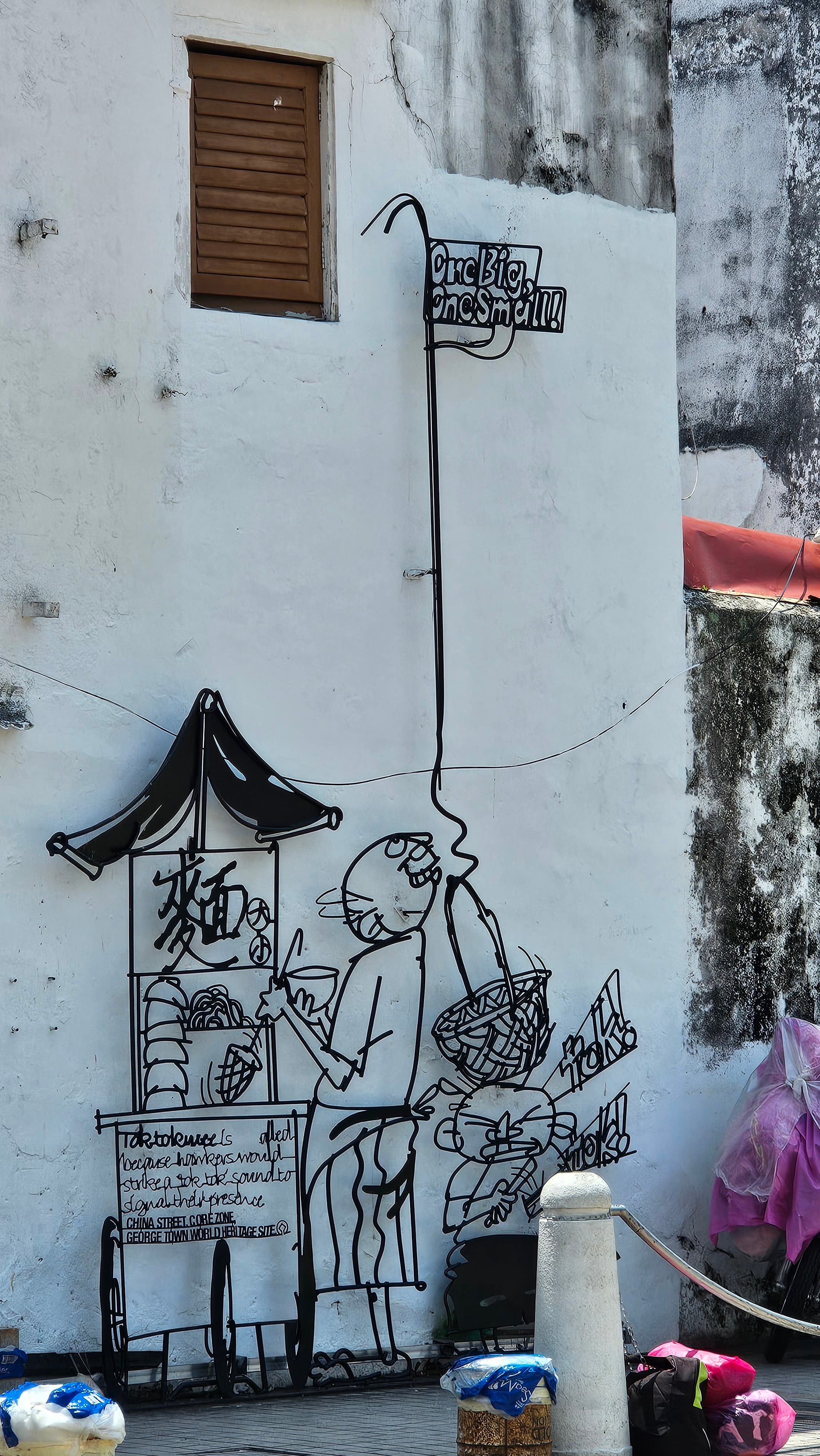 A steel-rod caricature sculpture from the Marking George Town project on a street corner