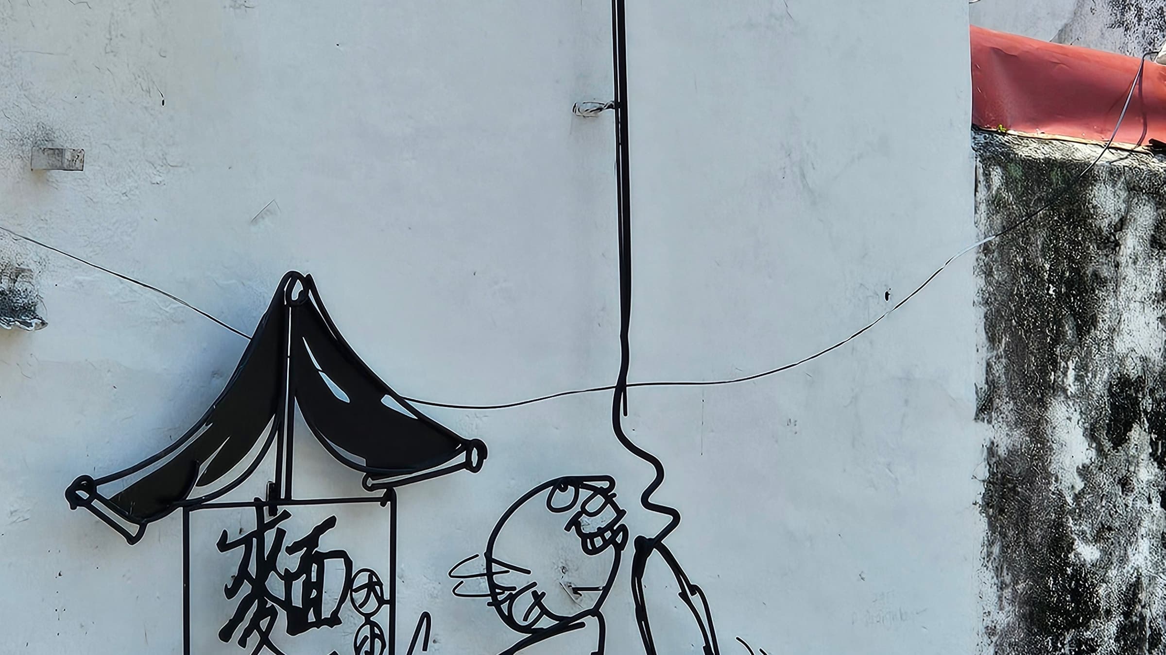 A steel-rod caricature sculpture from the Marking George Town project on a street corner
